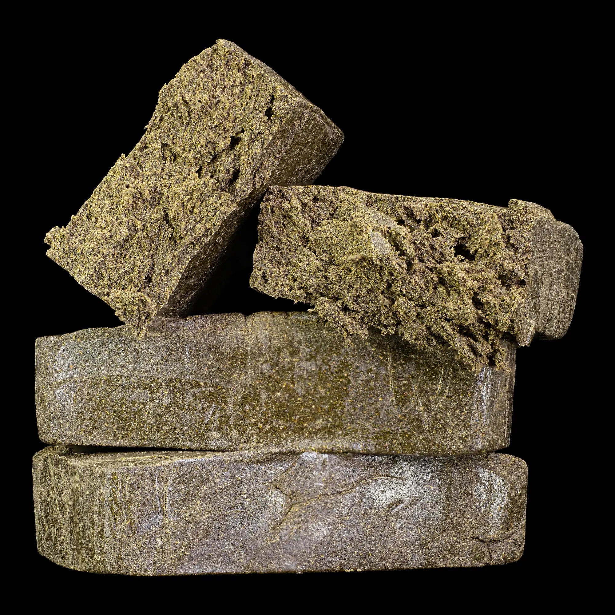 Manali Cream 40% THCA dry sift hash with dark oily exterior and soft golden core